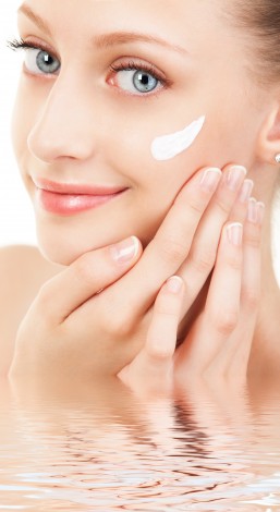 Cute woman applying cream to her face