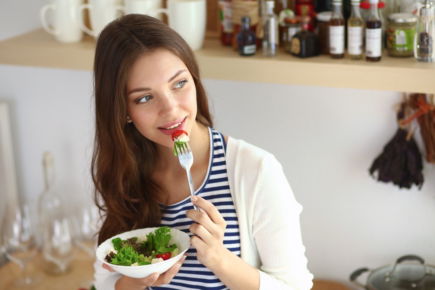 BM_Young woman eating salad and holding a mixed salad_95916957