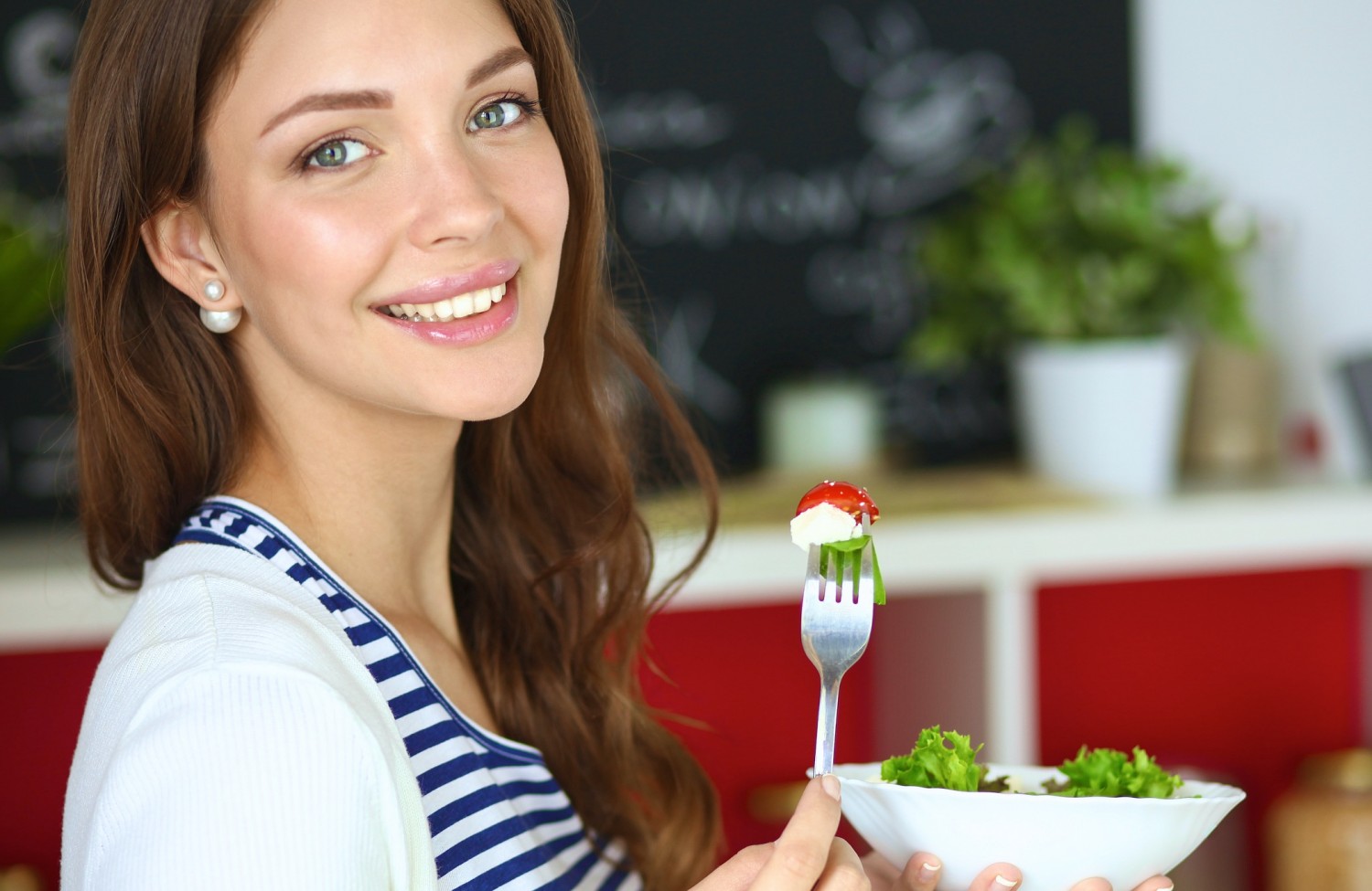 BM_Young woman eating salad and holding_95367192