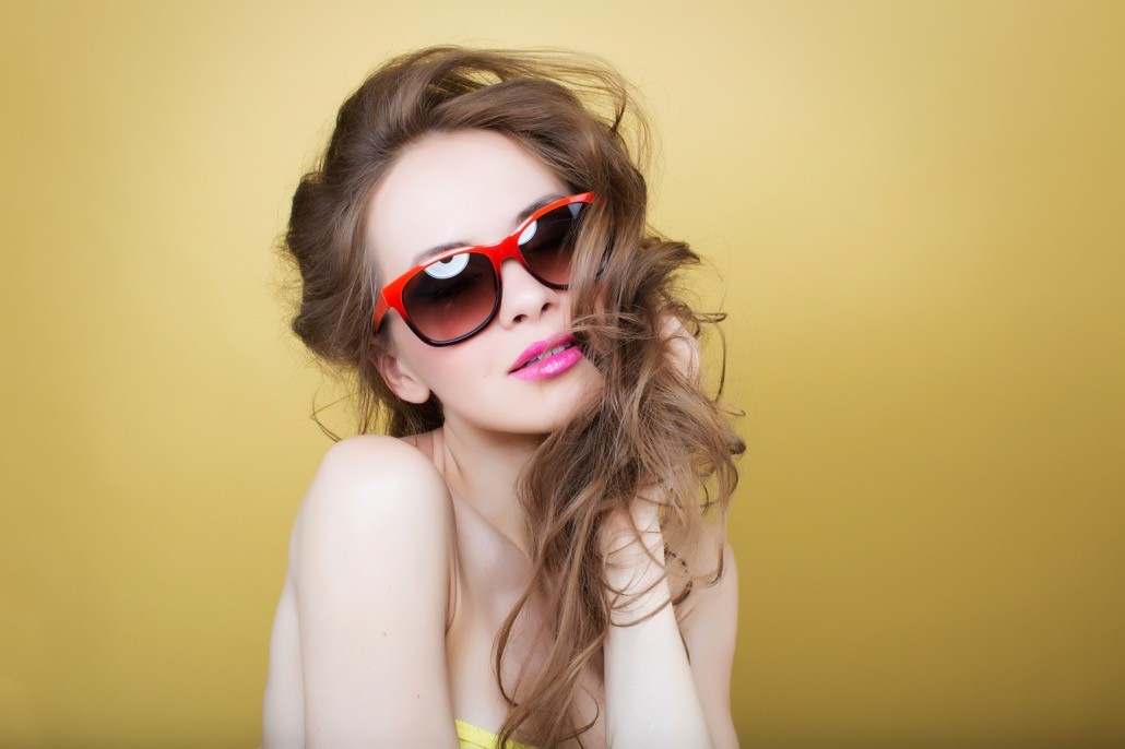 BM_Attractive surprised young woman wearing sunglasses on gold back_68259591