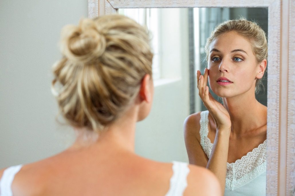 BM_Woman checking her skin in bathroom_107745383