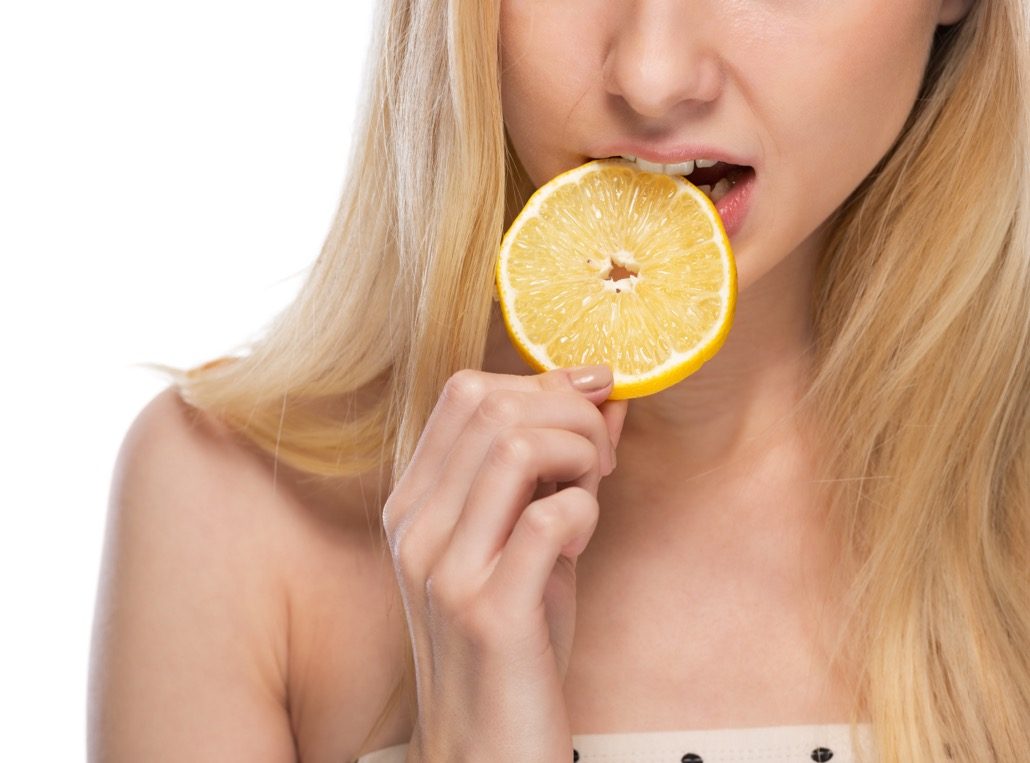 BM_Closeup on young woman eating lemon_61316143