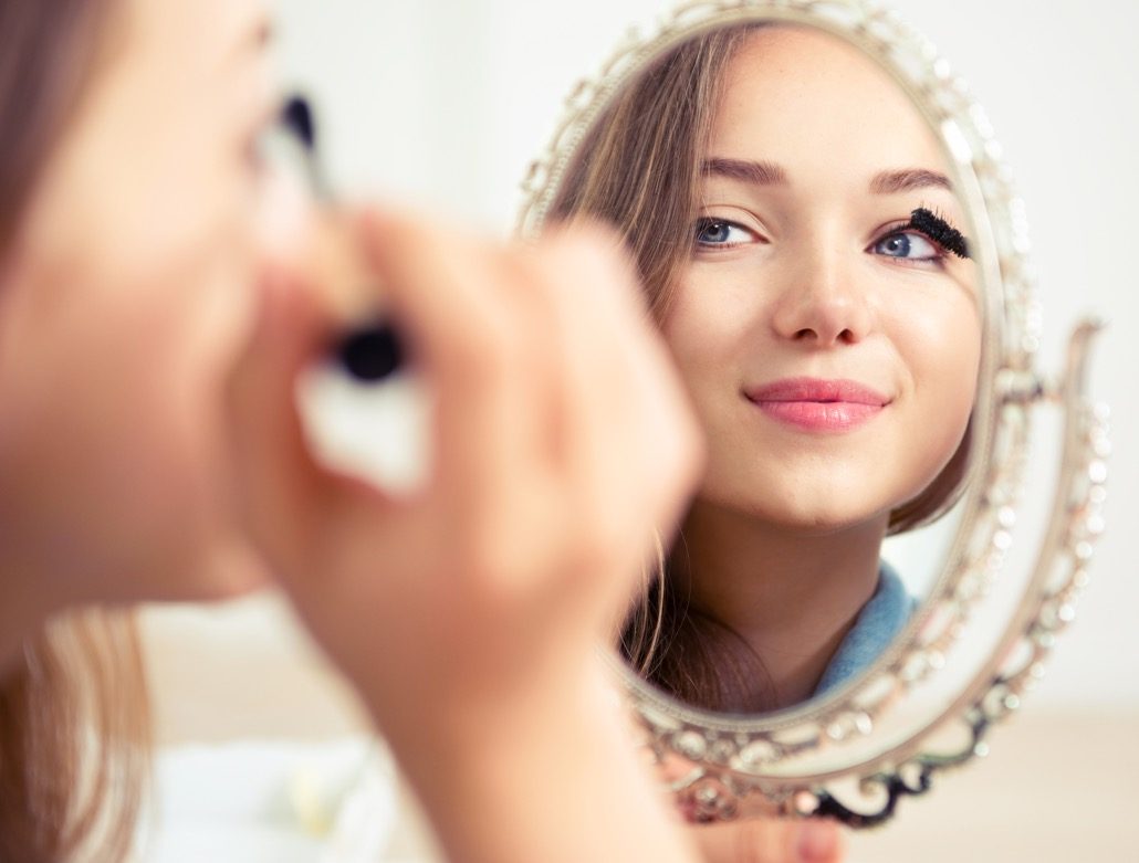 BM_Beauty model teenage girl looking in the mirror and applying mascara_87284991