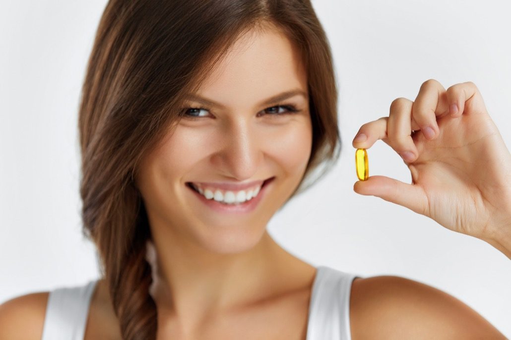 BM_Healthy Lifestyle. Woman Holding Pill With Fish Oil Omega-3_95726475