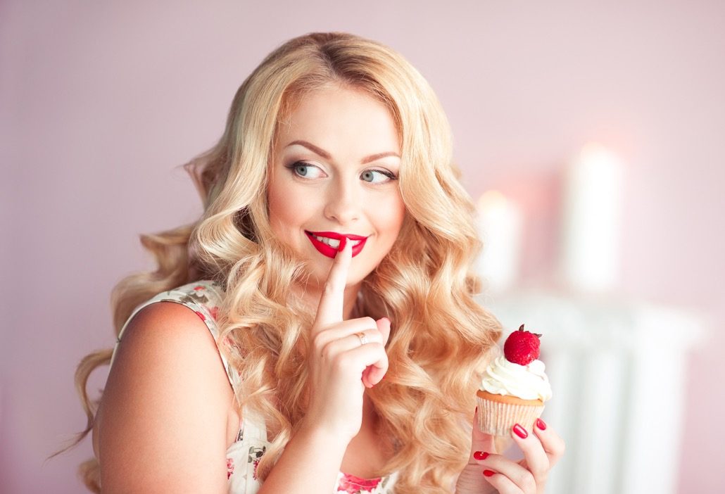 BM_Smiling woman holding cupcake with strawberry_114511402