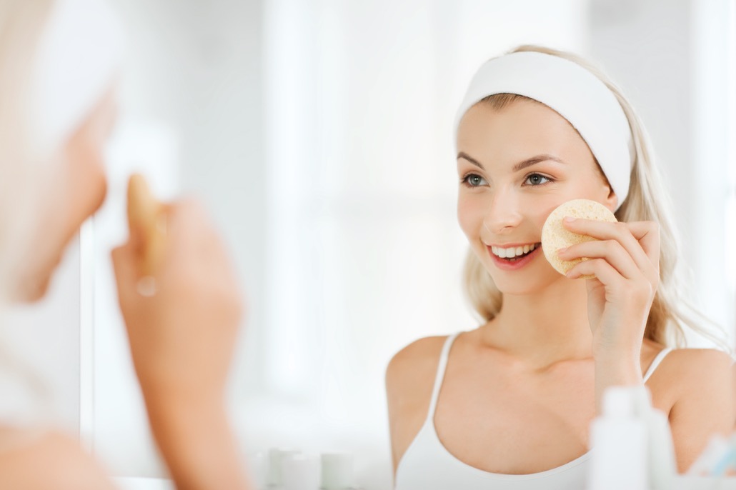 bm_young-woman-washing-face-with-sponge-at-bathroom_105111804
