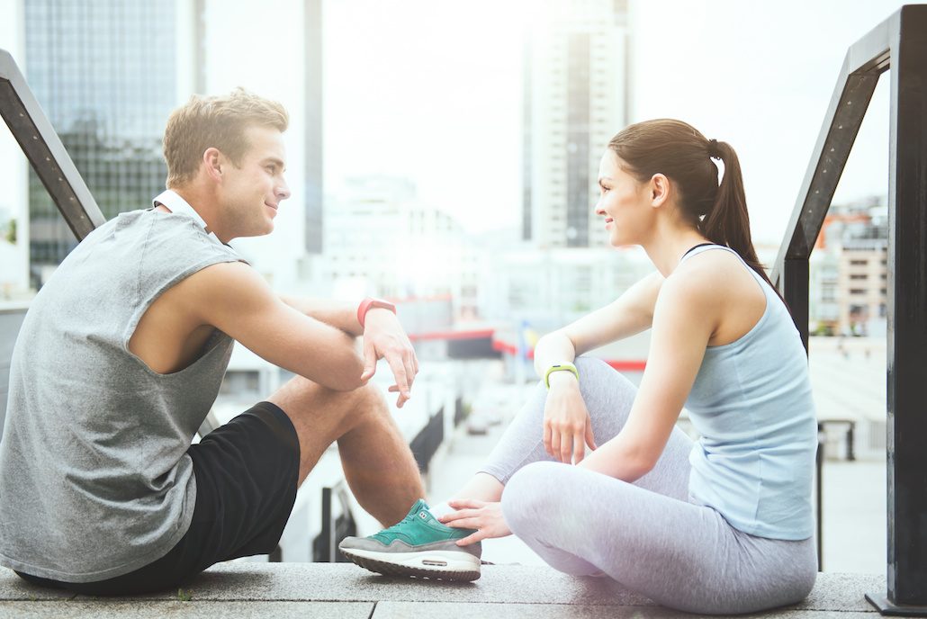 Happy relaxation together. Pretty young woman and a handsome athletic man sitting together and relaxing after working out in the city.