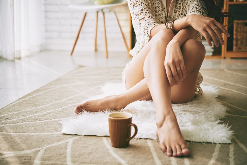 BM_Legs of woman sitting on the floor with cup of coffee_116795745